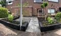 Voortuin met grote tegels en verhoogde borders 